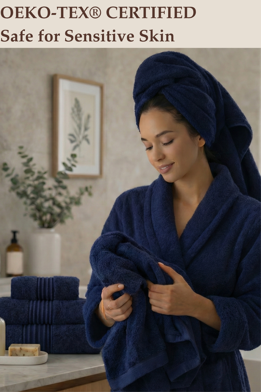 A woman in a bathroom setting holding a soft, OEKO-TEX certified navy blue Turkish cotton towel while wearing a matching luxury bathrobe