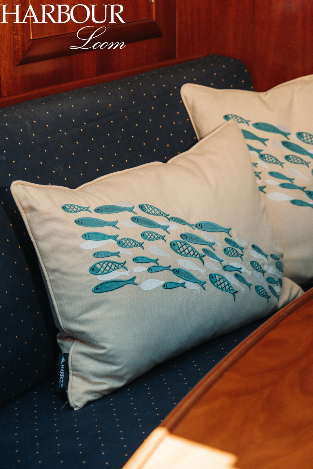 Decorative pillows with fish pattern on a navy cushion, branded 'Harbour Loom'.