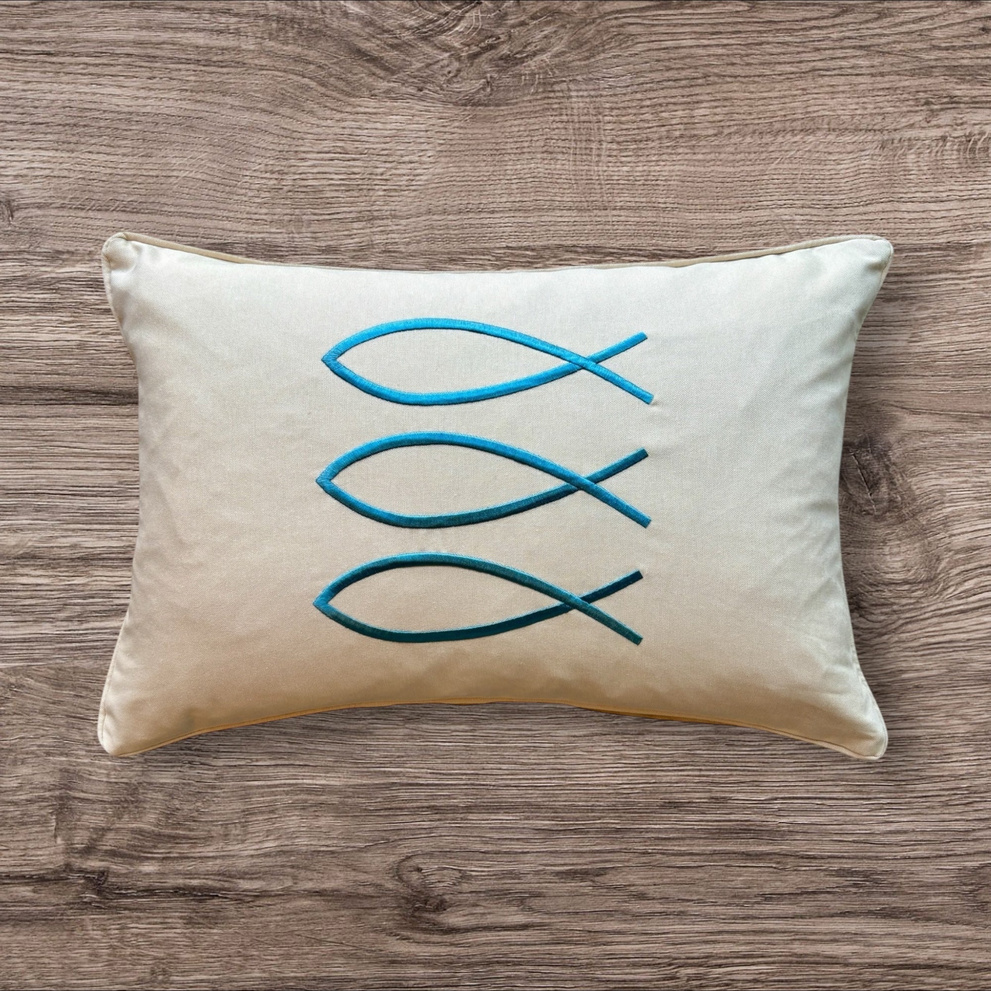 Trifin decorative pillow in sand color, measuring 14 x 20 inches (35 x 50 cm), featuring three overlapping teal fish-shaped embroidery designs on a rectangular beige fabric.