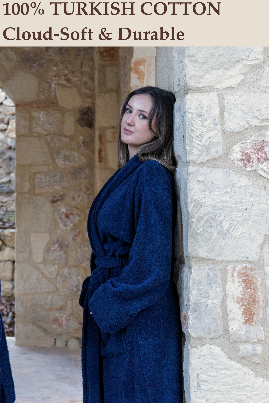 A woman leaning against a stone wall showcasing the thick, cloud-soft drape of the Harbour Loom 100% Turkish cotton robe