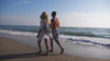 Vibrant beach towels in assorted colors and patterns, carried along a sunny shoreline during a beach walk, capturing a lively and carefree seaside vibe